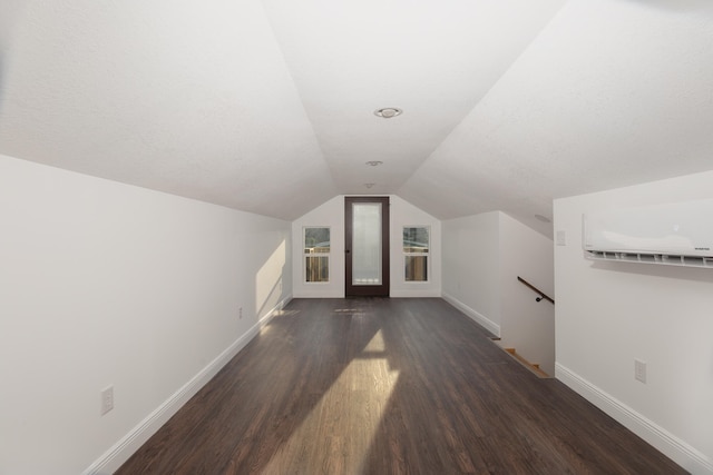 bonus room with an AC wall unit, lofted ceiling, and dark hardwood / wood-style flooring