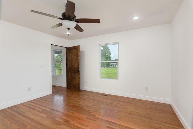 spare room featuring a healthy amount of sunlight, ceiling fan, and hardwood / wood-style flooring