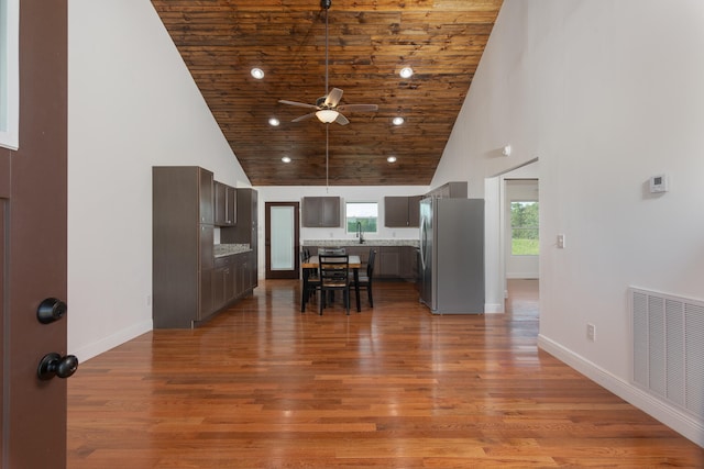 kitchen with wood ceiling, high vaulted ceiling, stainless steel refrigerator, ceiling fan, and hardwood / wood-style flooring