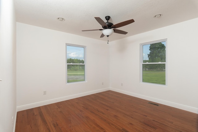 empty room featuring ceiling fan, a textured ceiling, and dark wood-type flooring