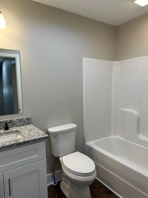 full bathroom with hardwood / wood-style floors, vanity, shower / bathtub combination, and toilet