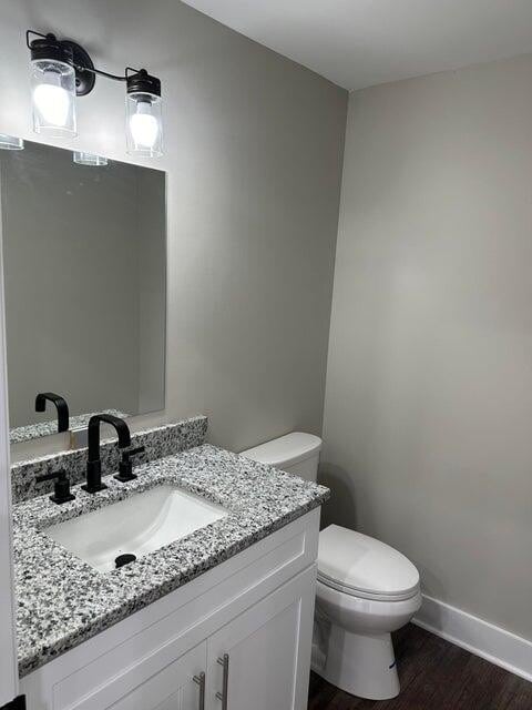 bathroom with wood-type flooring, vanity, and toilet