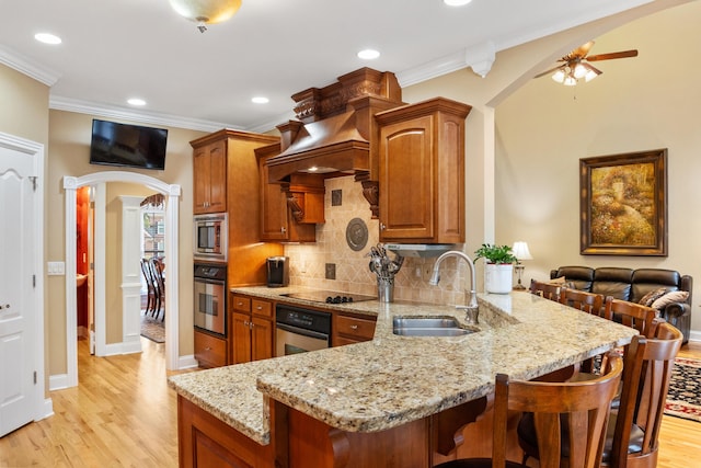 kitchen featuring light hardwood / wood-style floors, light stone countertops, stainless steel appliances, ceiling fan, and sink