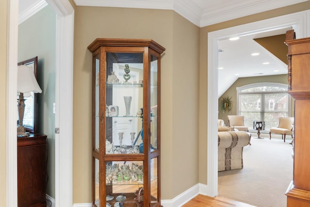 hallway with light carpet, crown molding, and vaulted ceiling