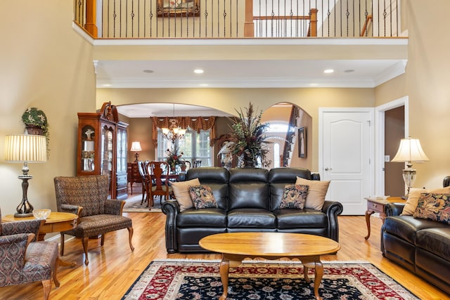 living room with ornamental molding, a high ceiling, a chandelier, and hardwood / wood-style floors