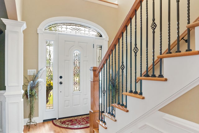 foyer entrance featuring light wood-type flooring and decorative columns