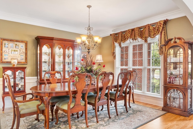 dining area with an inviting chandelier, a wealth of natural light, wood-type flooring, and crown molding