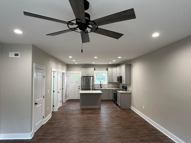 kitchen featuring appliances with stainless steel finishes, gray cabinetry, dark wood-type flooring, sink, and a kitchen island