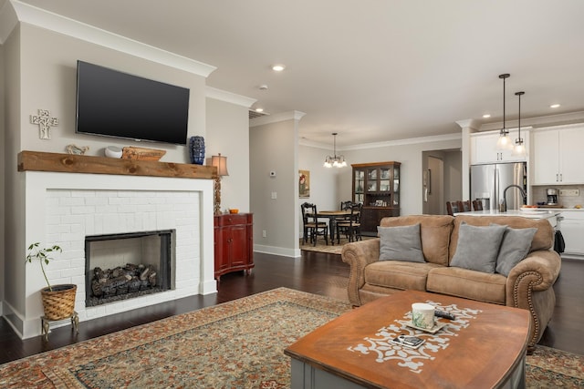 living room featuring a notable chandelier, a fireplace, crown molding, and dark hardwood / wood-style flooring