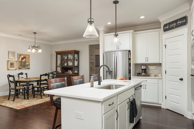 kitchen with pendant lighting, an island with sink, sink, appliances with stainless steel finishes, and dark hardwood / wood-style floors