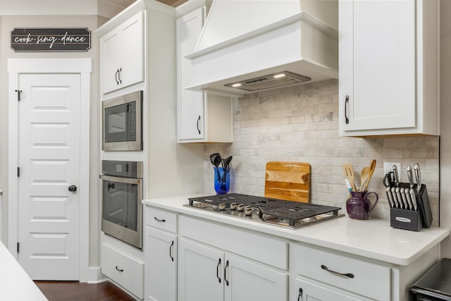 kitchen featuring white cabinets, custom exhaust hood, tasteful backsplash, stainless steel appliances, and dark hardwood / wood-style floors