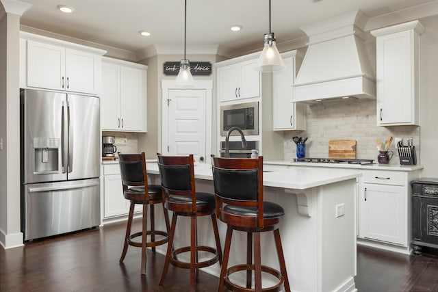 kitchen with an island with sink, custom exhaust hood, stainless steel appliances, and white cabinetry