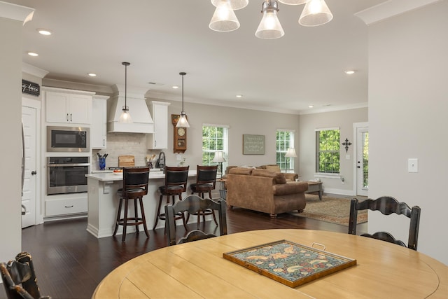 dining area featuring crown molding, sink, dark wood-type flooring, and a chandelier