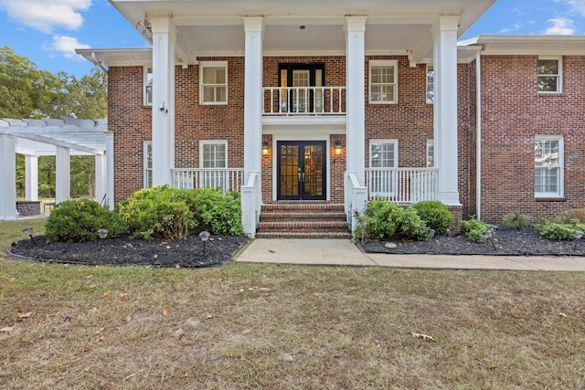 neoclassical home with a balcony, a pergola, and a front yard