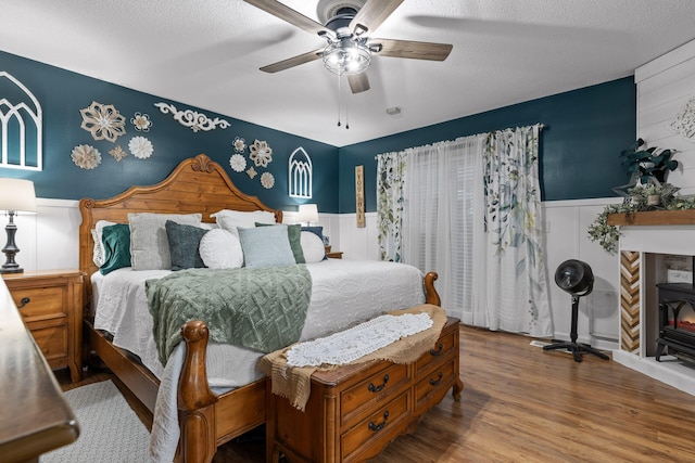 bedroom featuring ceiling fan, hardwood / wood-style flooring, and a textured ceiling