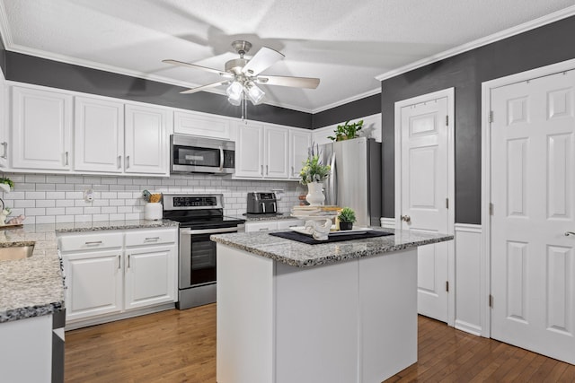 kitchen featuring a center island, hardwood / wood-style flooring, white cabinets, appliances with stainless steel finishes, and ceiling fan