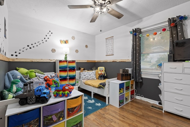 bedroom featuring ceiling fan, hardwood / wood-style floors, and a textured ceiling