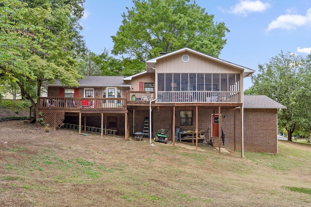 rear view of property with a lawn, a deck, and a sunroom