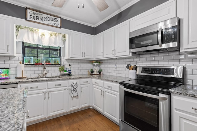 kitchen featuring white cabinets, stainless steel appliances, hardwood / wood-style floors, crown molding, and ceiling fan