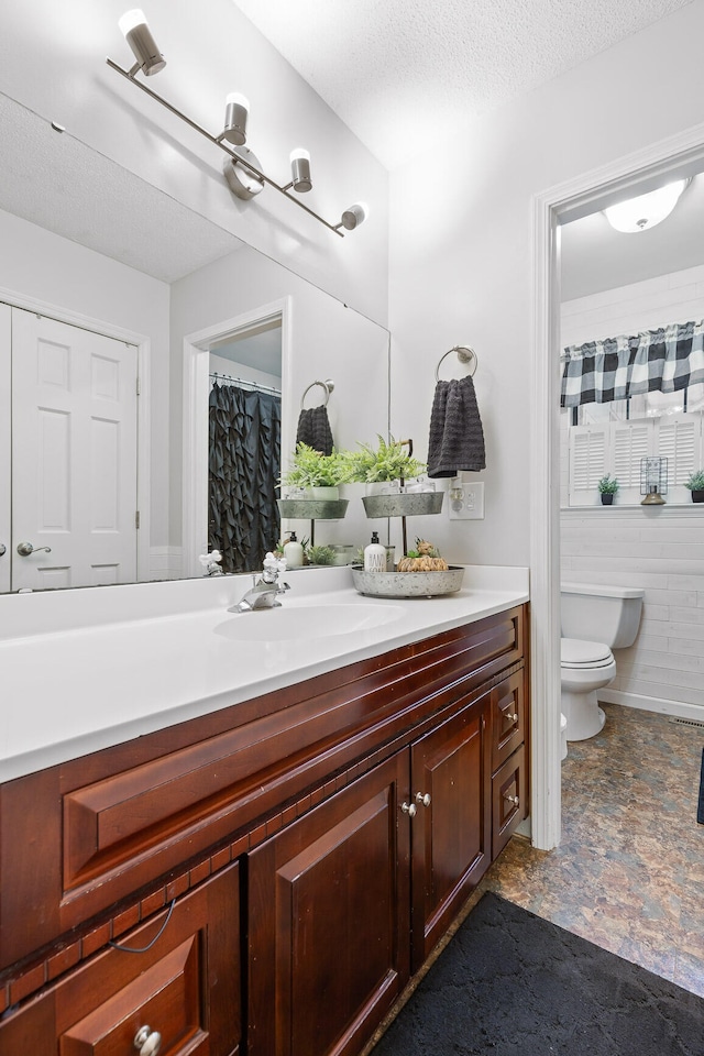 bathroom featuring vanity, toilet, and a textured ceiling