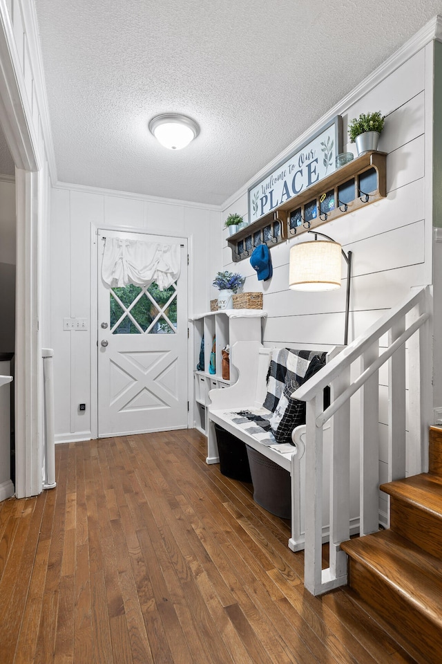 mudroom with wood-type flooring, a textured ceiling, and crown molding