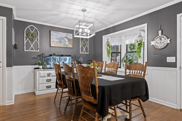 dining room featuring an inviting chandelier, a textured ceiling, ornamental molding, and hardwood / wood-style floors