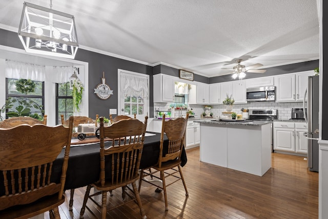 dining space with ceiling fan with notable chandelier, a textured ceiling, dark hardwood / wood-style floors, and crown molding