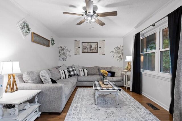 living room featuring ceiling fan, ornamental molding, a textured ceiling, and dark wood-type flooring