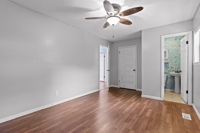 unfurnished bedroom with wood-type flooring, ensuite bath, and ceiling fan