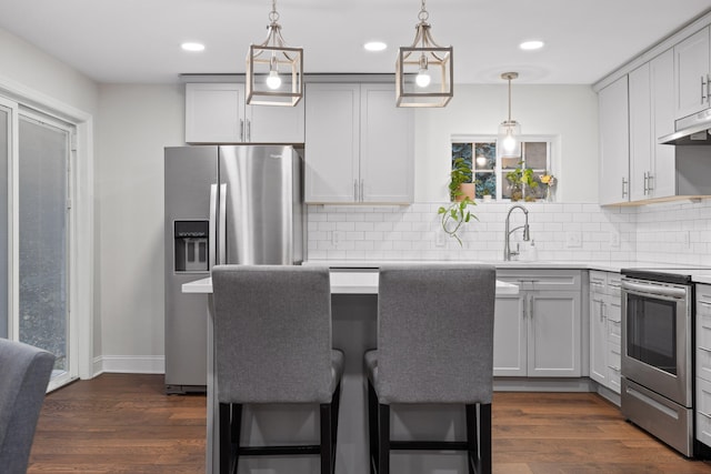 kitchen with pendant lighting, stainless steel appliances, dark wood-type flooring, and a breakfast bar