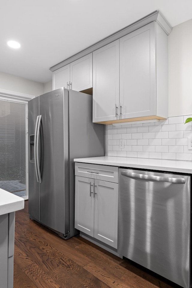 kitchen featuring stainless steel appliances, backsplash, dark wood-type flooring, and gray cabinetry