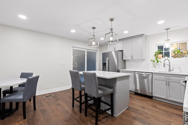 kitchen featuring hanging light fixtures, a center island, dark wood-type flooring, and stainless steel appliances