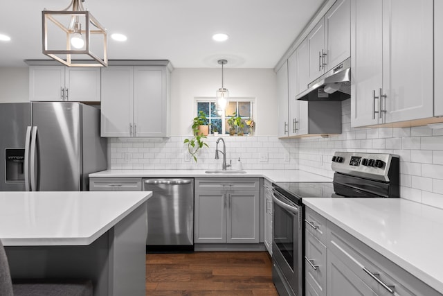 kitchen with hanging light fixtures, sink, gray cabinetry, stainless steel appliances, and dark hardwood / wood-style floors