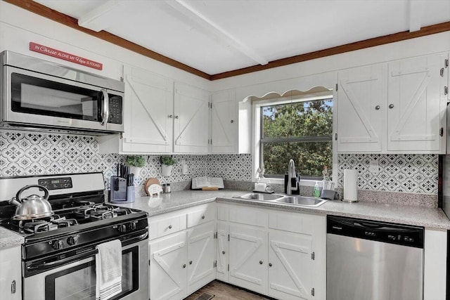 kitchen featuring beamed ceiling, tasteful backsplash, sink, white cabinetry, and stainless steel appliances