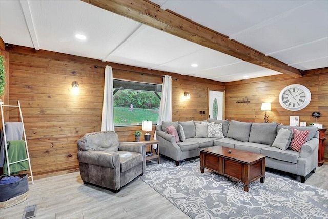 living room with beamed ceiling, light wood-type flooring, and wood walls