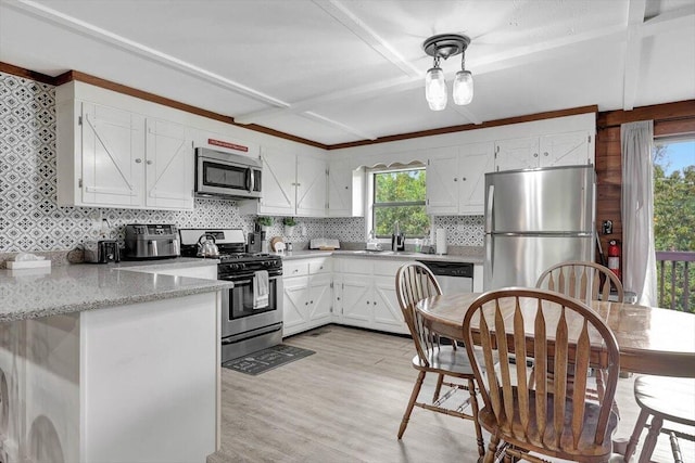 kitchen with light stone counters, backsplash, white cabinetry, appliances with stainless steel finishes, and light wood-type flooring