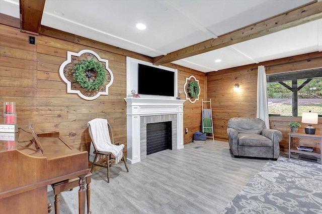 living room with beam ceiling, wooden walls, hardwood / wood-style floors, and a fireplace