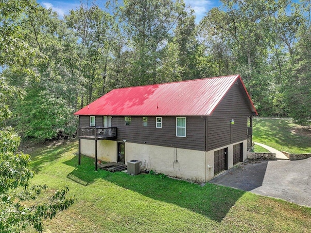 view of property exterior with cooling unit, a garage, a wooden deck, and a yard