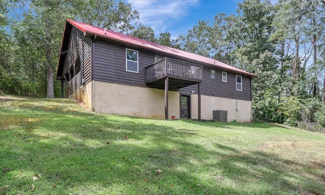 rear view of house featuring cooling unit, a yard, and a balcony