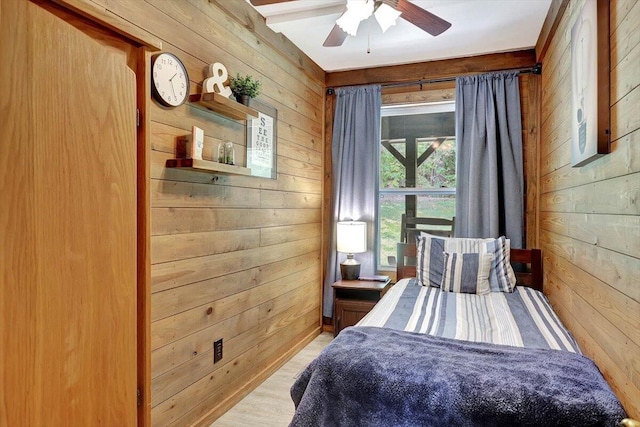 bedroom with light hardwood / wood-style floors, wood walls, and ceiling fan