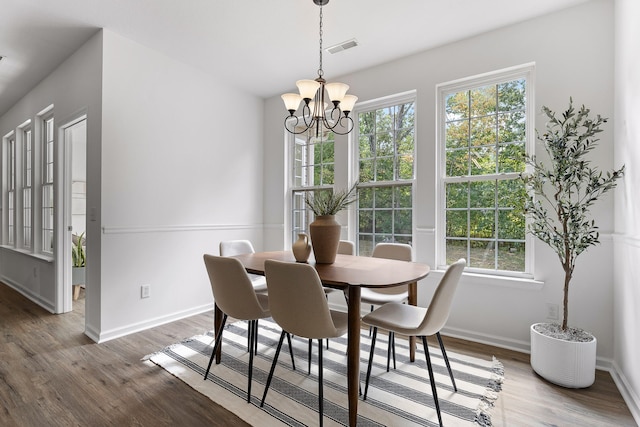 dining area with dark wood-type flooring and a notable chandelier