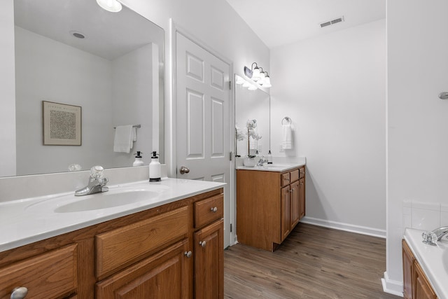 bathroom with wood-type flooring, a washtub, and vanity