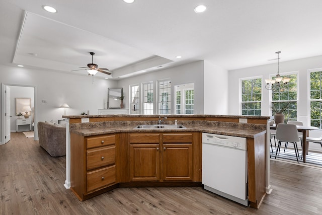 kitchen with white dishwasher, ceiling fan with notable chandelier, a raised ceiling, and sink