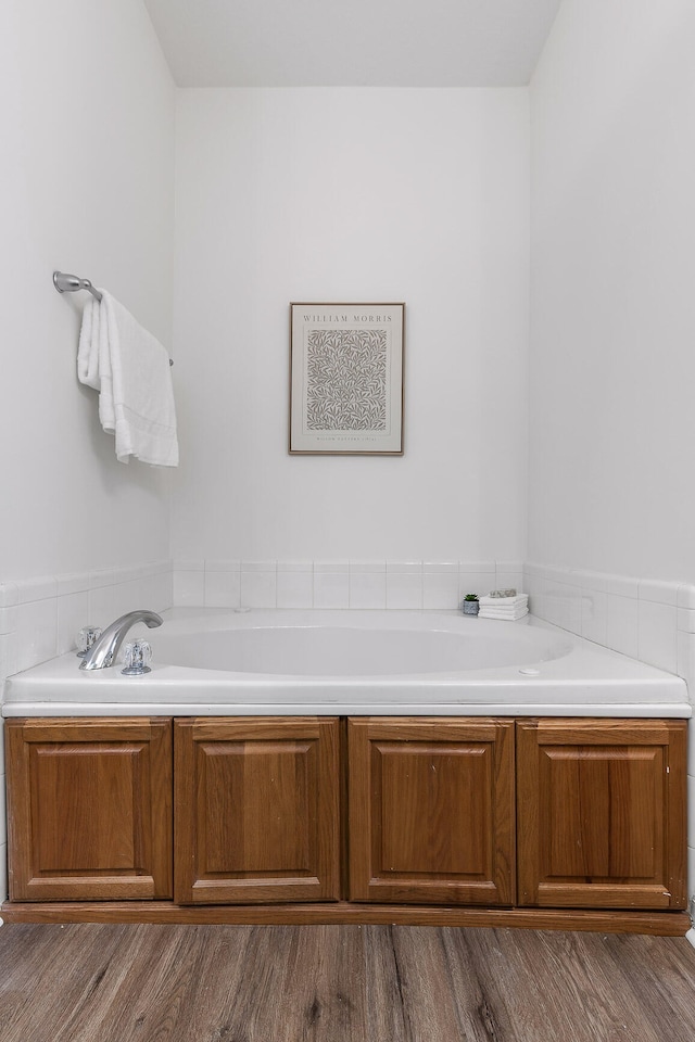 bathroom with a tub to relax in and wood-type flooring