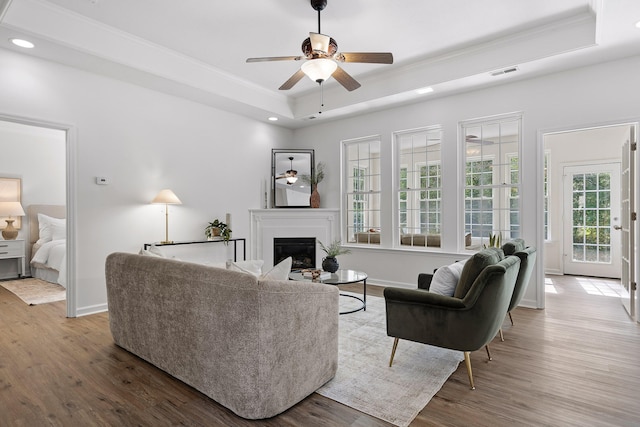 living room featuring a tray ceiling, ceiling fan, hardwood / wood-style flooring, and crown molding