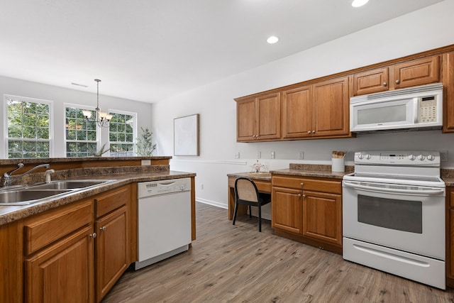 kitchen with sink, light hardwood / wood-style flooring, an inviting chandelier, white appliances, and decorative light fixtures