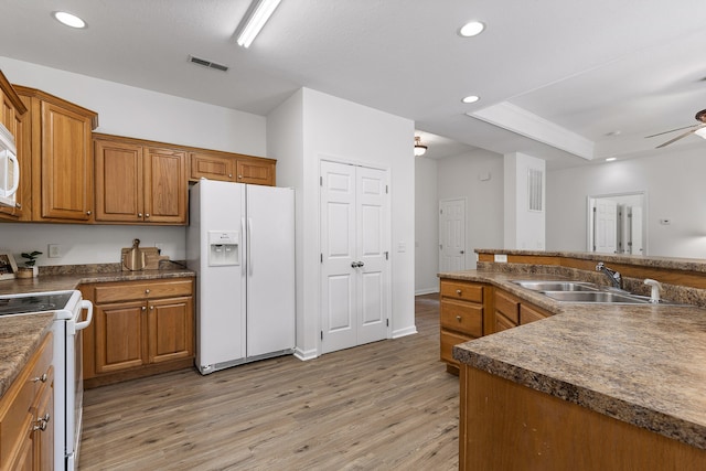 kitchen with white appliances, hardwood / wood-style floors, ceiling fan, and sink