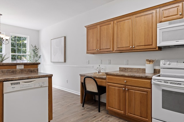 kitchen featuring light wood-type flooring, hanging light fixtures, white appliances, and a notable chandelier