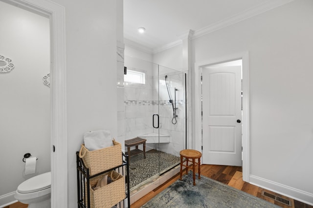 bathroom featuring toilet, a shower with door, crown molding, and hardwood / wood-style floors