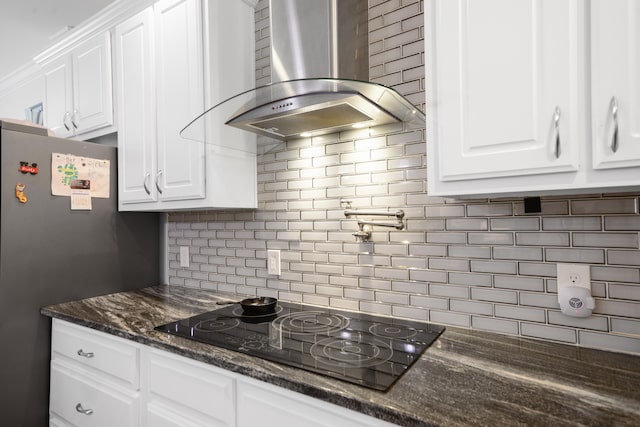 kitchen featuring exhaust hood, white cabinetry, black electric stovetop, dark stone counters, and decorative backsplash